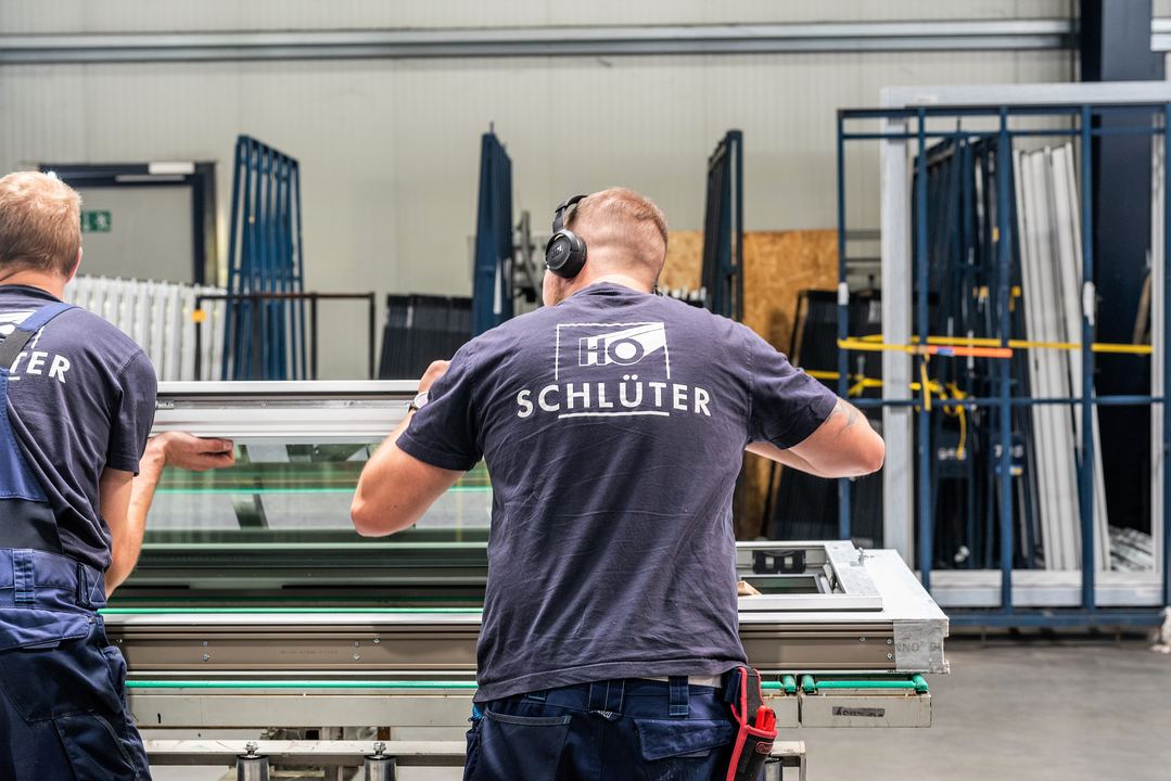 Zwei Mitarbeiter in der Fertigungshalle bei der Arbeit an einem Element.